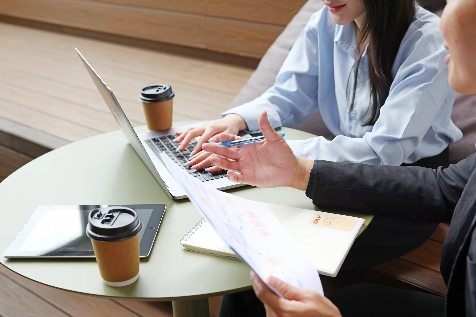 Hands reviewing documents beside a laptop