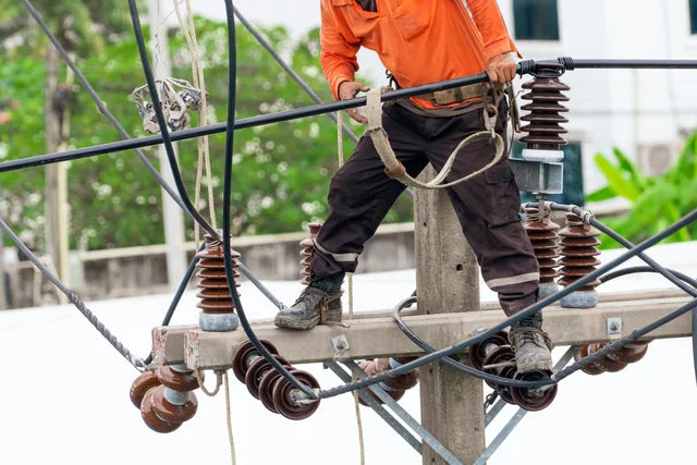 An electricity worker maintaining overhead power equipment