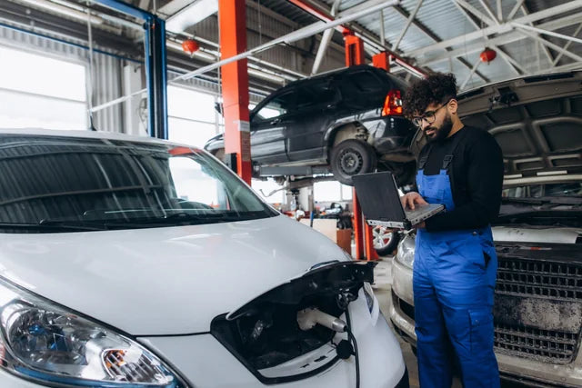 An automotive technician inspecting a vehicle in a workshop