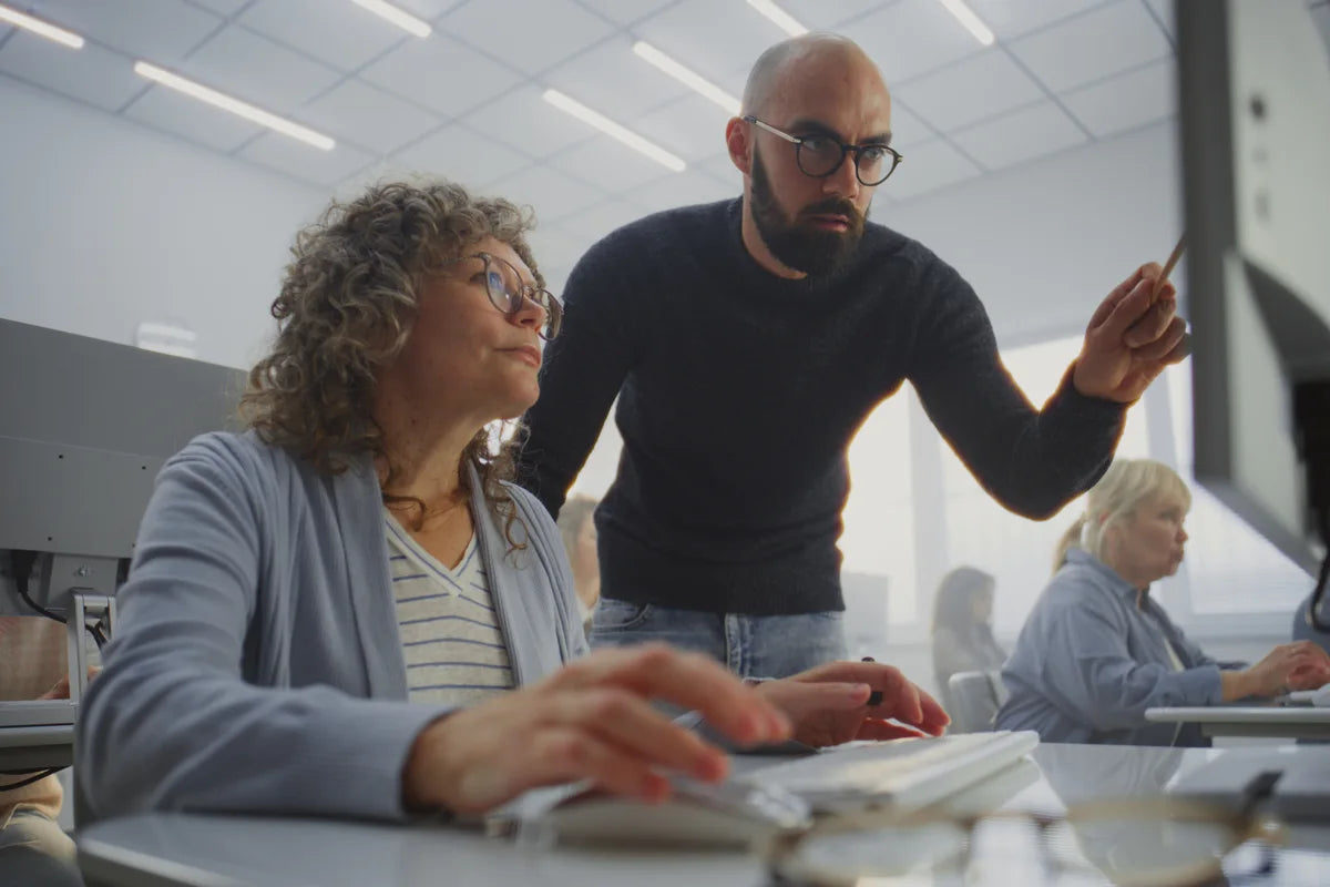 An educator guiding a learner at a computer