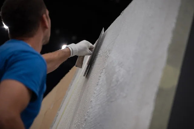 A tradesperson applying plaster to an interior wall