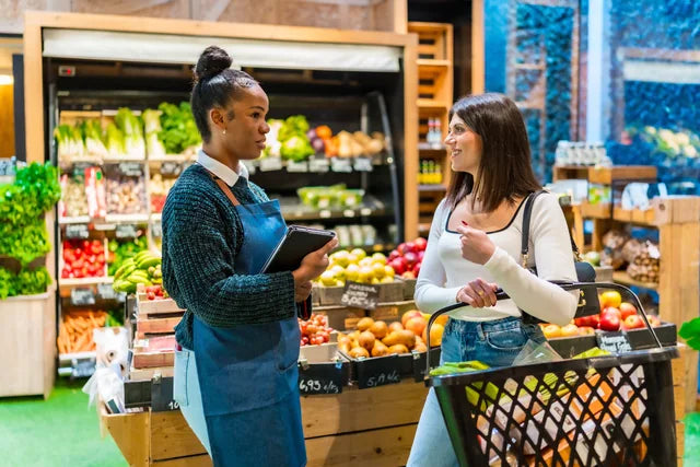 A retail team member helping a customer choose produce