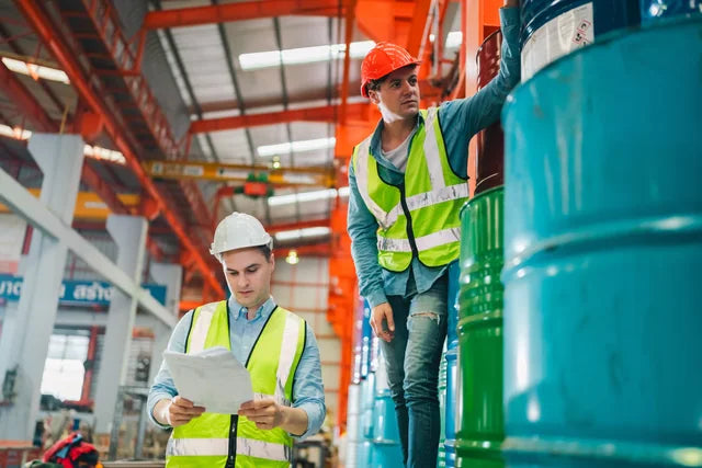 Workers reviewing safety documentation in an industrial warehouse